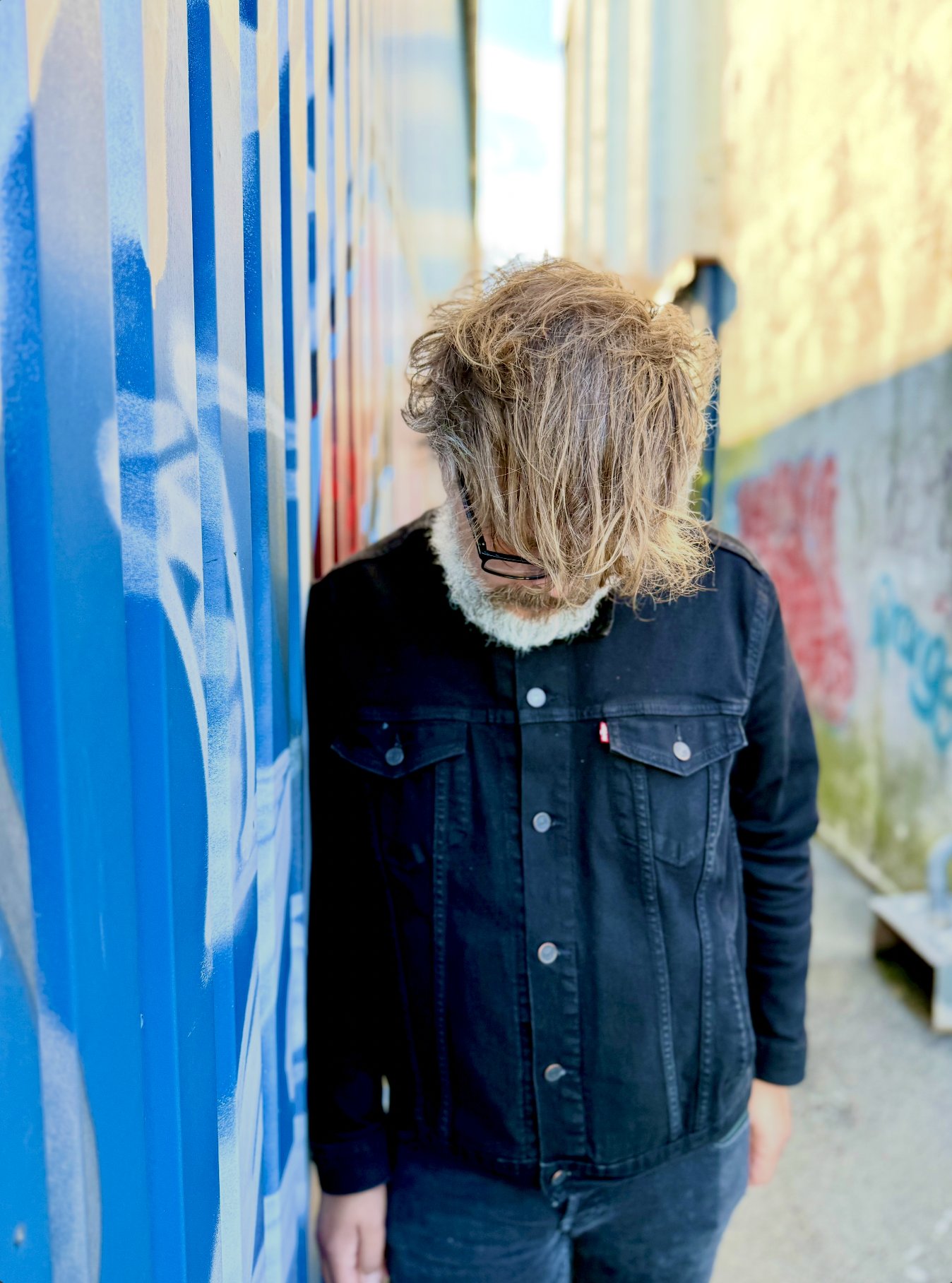 Elephant Moon portrait: head bowed beside a blue shipping container